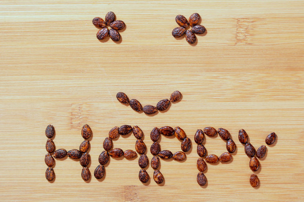 Семена арбуза на деревянном фоне, смайлик со счастливым словом
 - Фото, изображение