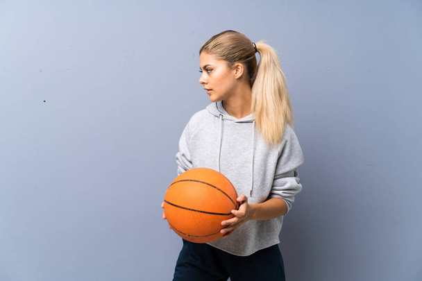 Teini tyttö pelaa koripalloa yli harmaa seinä
 - Valokuva, kuva