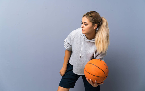 灰色の壁の上にバスケットボールをしているティーンエイジャーの女の子 - 写真・画像