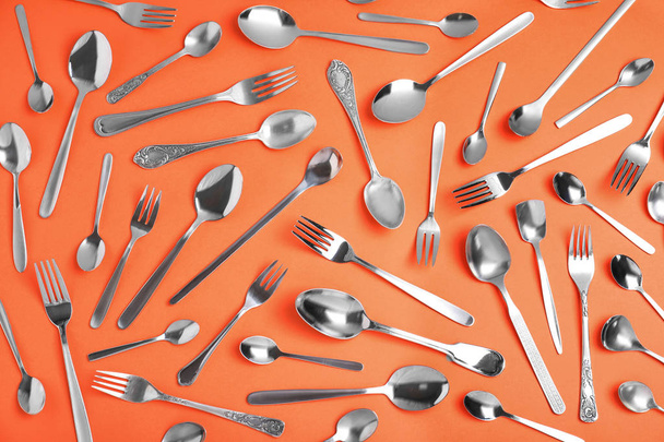 Set of new silver cutlery on coral background, flat lay - Φωτογραφία, εικόνα