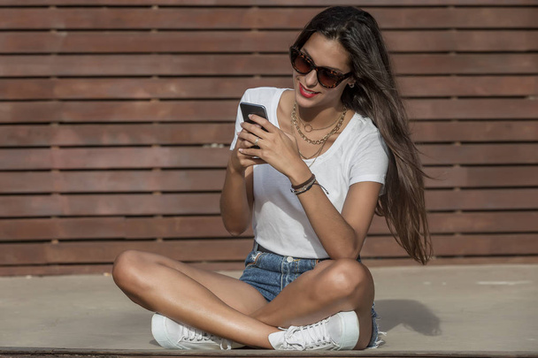 Positive female surfing cellphone while relaxing on stage - Photo, Image