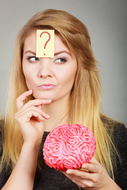 Mujer pensando y sosteniendo cerebro falso
 - Foto, imagen