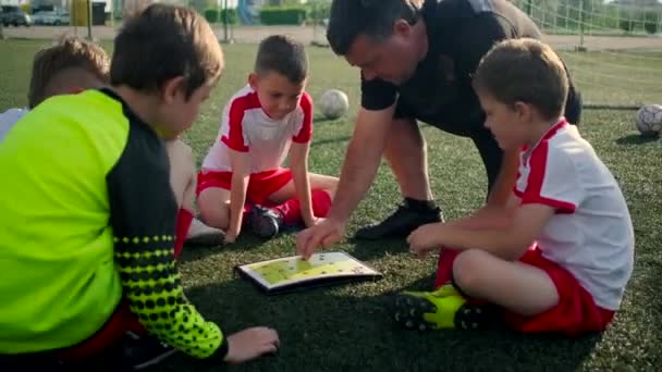 Junior ποδοσφαιρική ομάδα προπονητής δείχνει το σχέδιο των παιδιών παιχνίδι - Πλάνα, βίντεο
