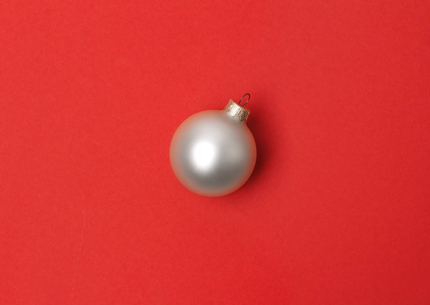Λευκή Χριστουγεννιάτικη μπάλα πάνω από κόκκινο χαρτί φόντο. - Φωτογραφία, εικόνα
