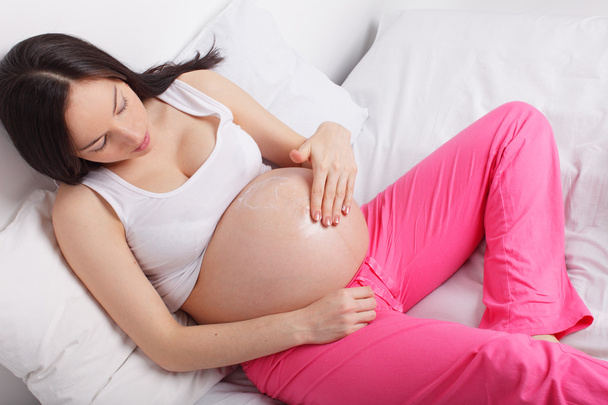 Pregnant woman putting a cream on a stomach - Foto, immagini