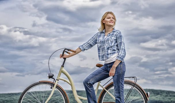 Active leisure and healthy activity. Girl ride cruiser model bicycle. Healthiest most environmentally friendly and most satisfying forms of self transportation. Woman rides bicycle sky background - Foto, Imagem