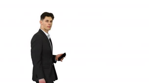 Handsome suspicious businessman walking by with a phone in a hand and with briefcase looking to the side on white background. - Video
