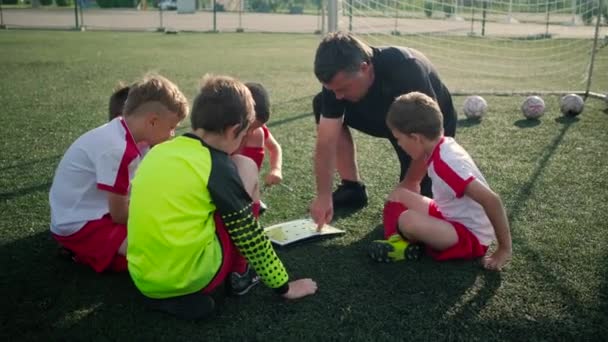 Trainer zeigt kleinen Jungen Fußballplatz-Plan - Filmmaterial, Video