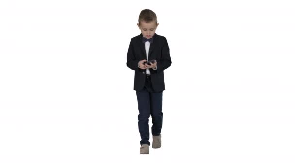 Маленький мальчик в костюмах ходить и использовать смартфон на белом фоне
. - Кадры, видео