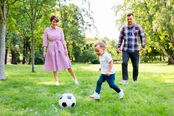 ευτυχισμένη οικογένεια παίζοντας ποδόσφαιρο στο καλοκαιρινό πάρκο - Φωτογραφία, εικόνα