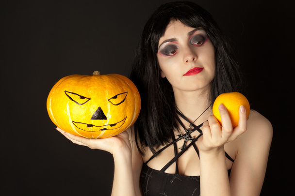 Woman with halloween makeup holding a pumpkin and an orange - Foto, Imagem