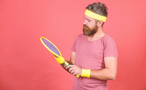 Tennis player retro fashion. Tennis sport and entertainment. Athlete hipster hold tennis racket in hand red background. Play tennis for fun. Man bearded hipster wear sport outfit. Reach top again - Photo, Image