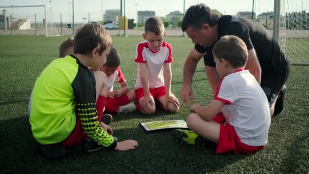 Ο προπονητής διδάσκει μικρά αγόρια της τακτικής του ποδοσφαίρου σε ανοιχτό στάδιο - Πλάνα, βίντεο