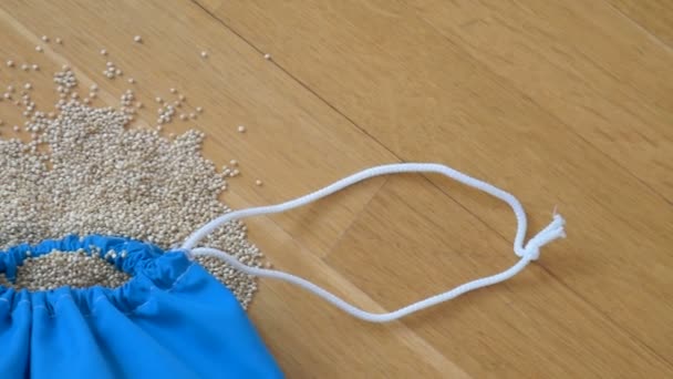 Ansicht von weißen Quinoa-Samen in blauer Mehrwegverpackung auf Holzgrund. Konzept der gesunden Ernährung - Filmmaterial, Video