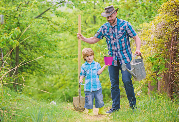 happy earth day. Family tree nursering. Eco farm. small boy child help father in farming. watering can, pot and shovel. Garden equipment. father and son in cowboy hat on ranch. Fond of horticulture - Фото, зображення