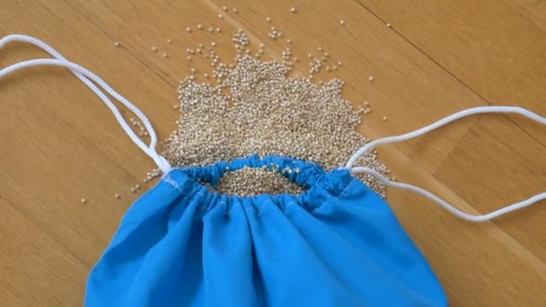 Top uitzicht van witte quinoa zaden in blauwe herbruikbare pakket op houten achtergrond. Gezond eetconcept - Video