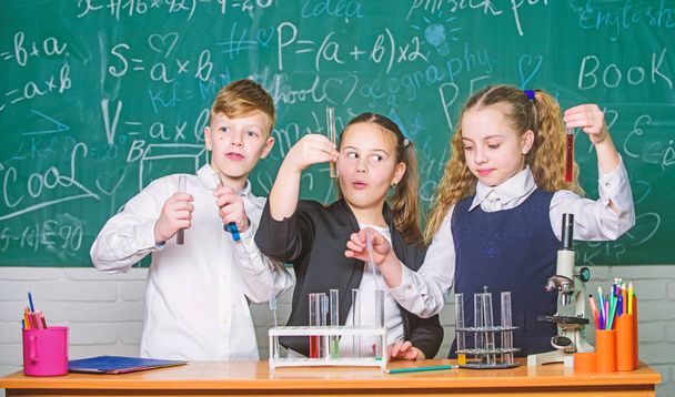 Check result. Girls and boy student conduct experiment with liquids. Teamwork concept. Test tubes with colorful liquid substances. Study of liquid states. Group school pupils study chemical liquids - Foto, immagini