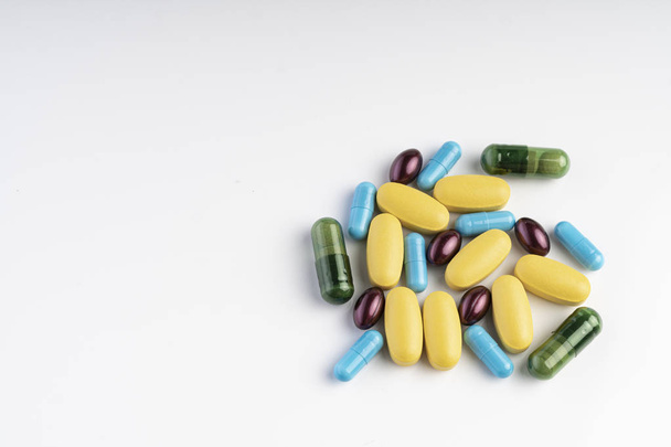 Yellow, blue, green and purple pills isolated on a white background. Diseases - Zdjęcie, obraz