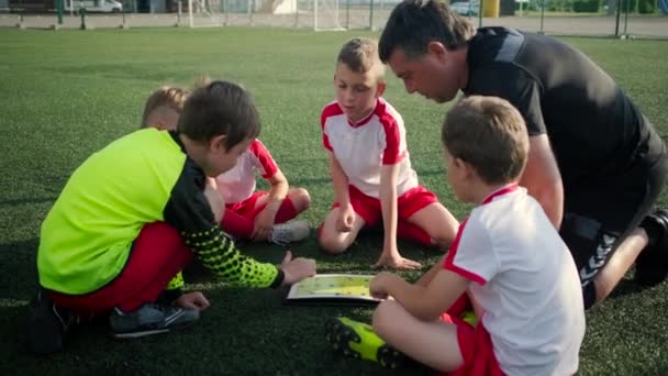 Fußballteam aus kleinen Jungen und Trainer diskutieren über Taktik - Filmmaterial, Video