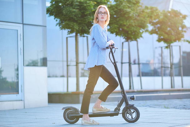 Young woman is enjoying riding on her new scooter - Zdjęcie, obraz