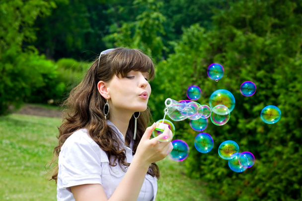 Jeune fille soufflant bulles de savon au printemps vert
 - Photo, image