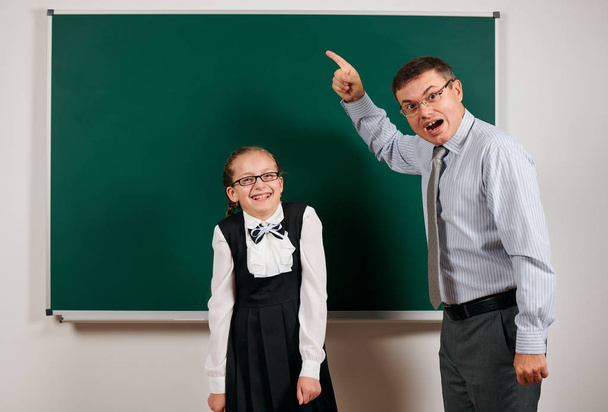 rozzlobený učitel zakřičel na školku a pózující v černé tabuli-zpátky do školy a vzdělávacího konceptu - Fotografie, Obrázek