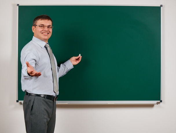 Portrait of a man dressed as a school teacher in business suit, posing at blackboard background - learning and education concept - Photo, Image