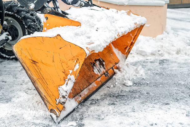 Close-up snowplow of big tractor machine removing and cleaning snow after storm on icy road or city street at alpine mountain resort region in winter - Photo, Image