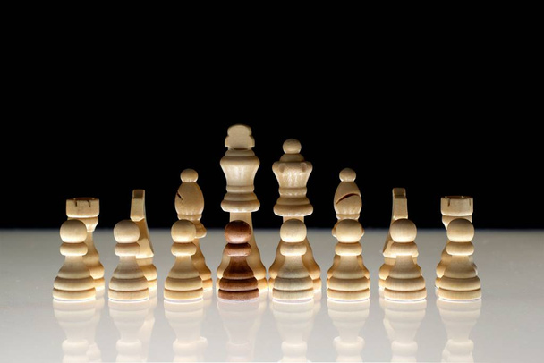 Λευκός σχηματισμός σκακιού με ένα ενιαίο μαύρο κομμάτι ως έννοια για μυστικές επιχειρήσεις, διήθηση, φυλετική ένταση, εθνοτικές μειονότητες. - Φωτογραφία, εικόνα