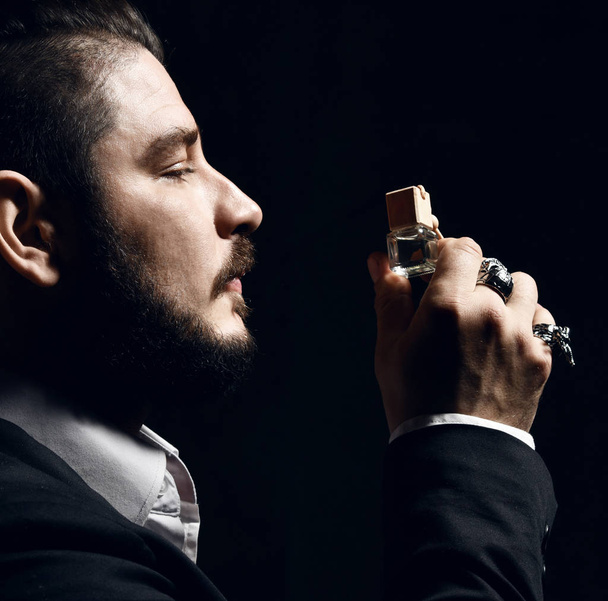Brutal man with beard and modern hairstyle smell auto perfume wear business classic suit - Фото, зображення