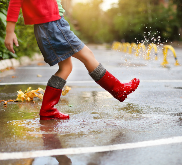 Gyermek visel piros eső csizma, beugrott egy pocsolya - Fotó, kép