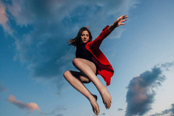 Силует красивої стрибаючої жінки проти блакитного неба на заході сонця
 - Фото, зображення