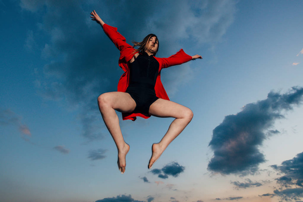 Siluetti nuori nainen hyppää auringonlaskua vastaan
 - Valokuva, kuva