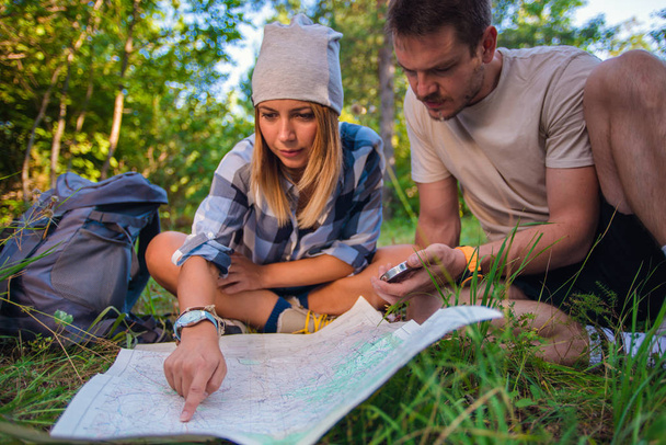 若いカップル、森の中に地図とコンパスを使用して navigasting です。夏の山でハイキング コンセプト - 写真・画像