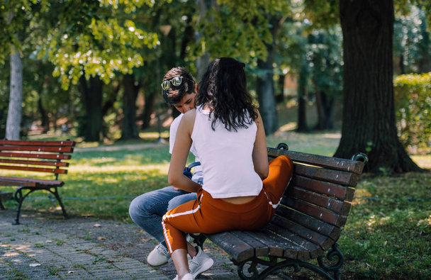 Молодая влюбленная пара, сидящая вместе на скамейке в летнем парке
 - Фото, изображение