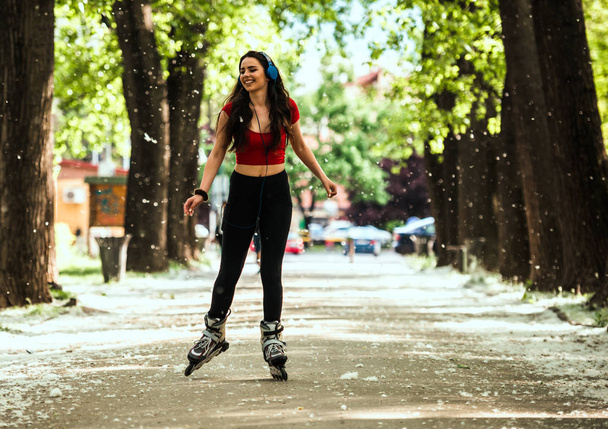 Rolschaatsen op mooi meisje tijdens het rijden skaters in stedelijk park - Foto, afbeelding