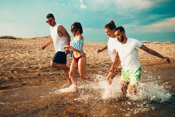 Люди наслаждаются в воде на солнечном пляже на закате
 - Фото, изображение