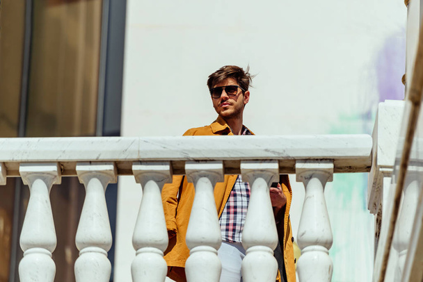 バルコニーでリラックス黄色のコートと現代のビジネスマン - 写真・画像