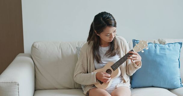 Mulher jogar ukulele em casa
 - Foto, Imagem