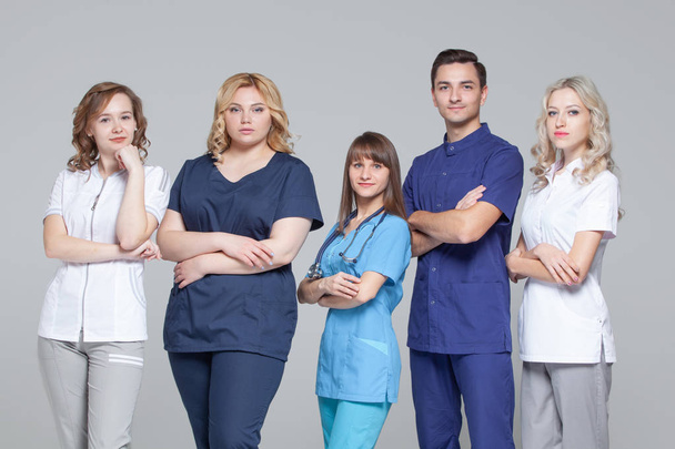 Successful team of medical doctors are looking at camera while standing on grey background - Foto, Imagen