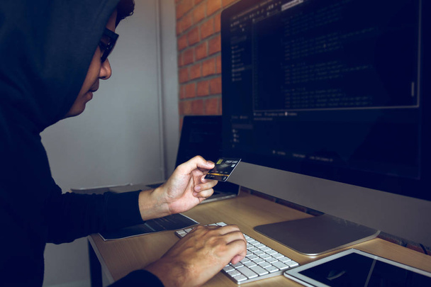 Hacker a háttérben dolgozó számítógép és a Holding hitelkártya - Fotó, kép