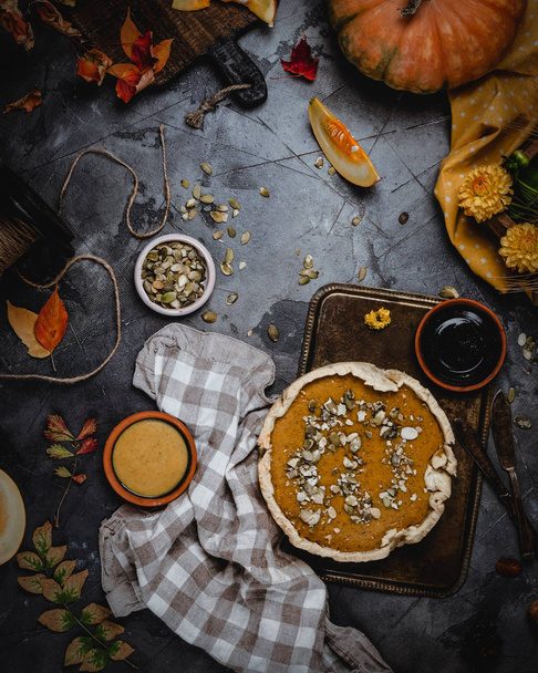 pumpkin pie decorated with pumpkin seeds on metal tray with textile  - Foto, Imagen