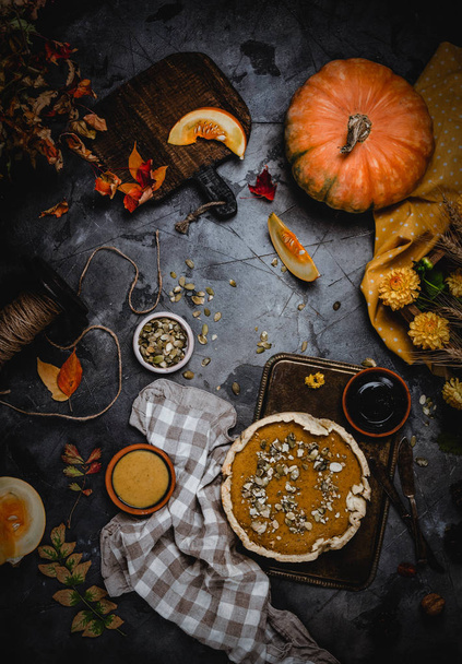 pumpkin pie decorated with pumpkin seeds on metal tray with textile  - Fotó, kép