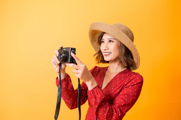 Portrait of fashionable young woman with vintage film camera for travelling concept. Isolated on orange background - Photo, Image