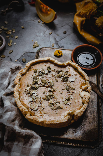 pumpkin pie decorated with pumpkin seeds on metal tray with textile  - Foto, Bild