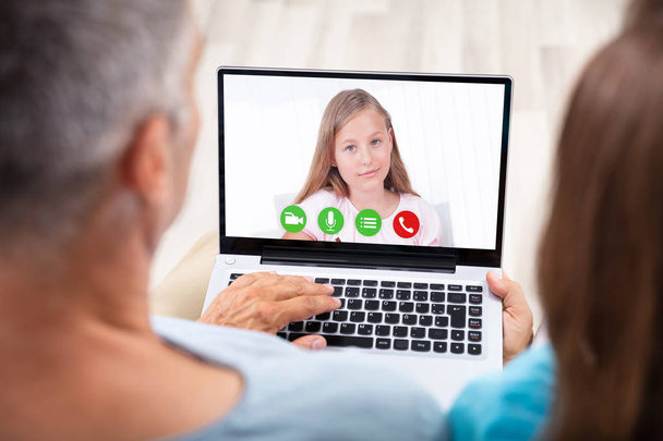Couple Video Conferencing With Their Daughter On Laptop - Foto, afbeelding