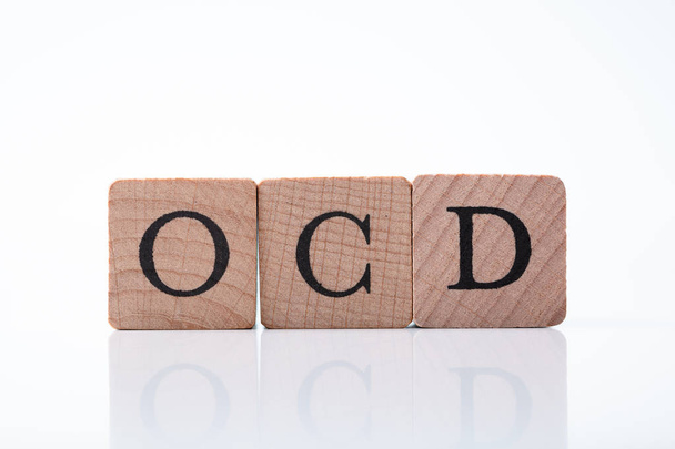 Close-up Of Ocd Text On Wooden Block Over Reflective Desk - Foto, Bild