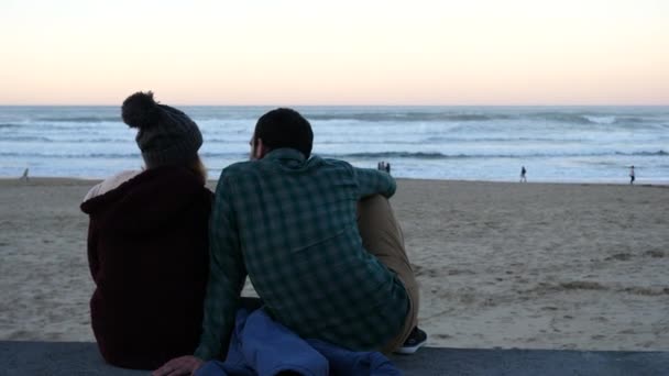 Сан-Себастьян, Испания - 30 декабря 2017 года: пара, сидящая на каменной стене с видом на море
. - Кадры, видео