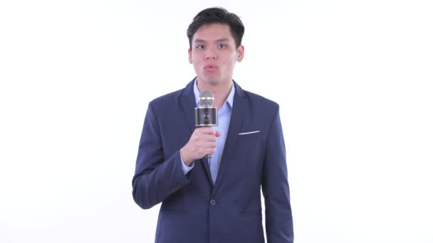Gelukkig jonge Aziatische zakenman als nieuwslezer met behulp van microfoon - Video