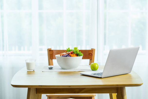 Scéna zeleniny v bílém Bolu s mlékem z brýlí a jablek s přenosným notebookem na dřevěném stole s židlí v moderním domově, v pořádku a v tvrdé koncepci - Fotografie, Obrázek